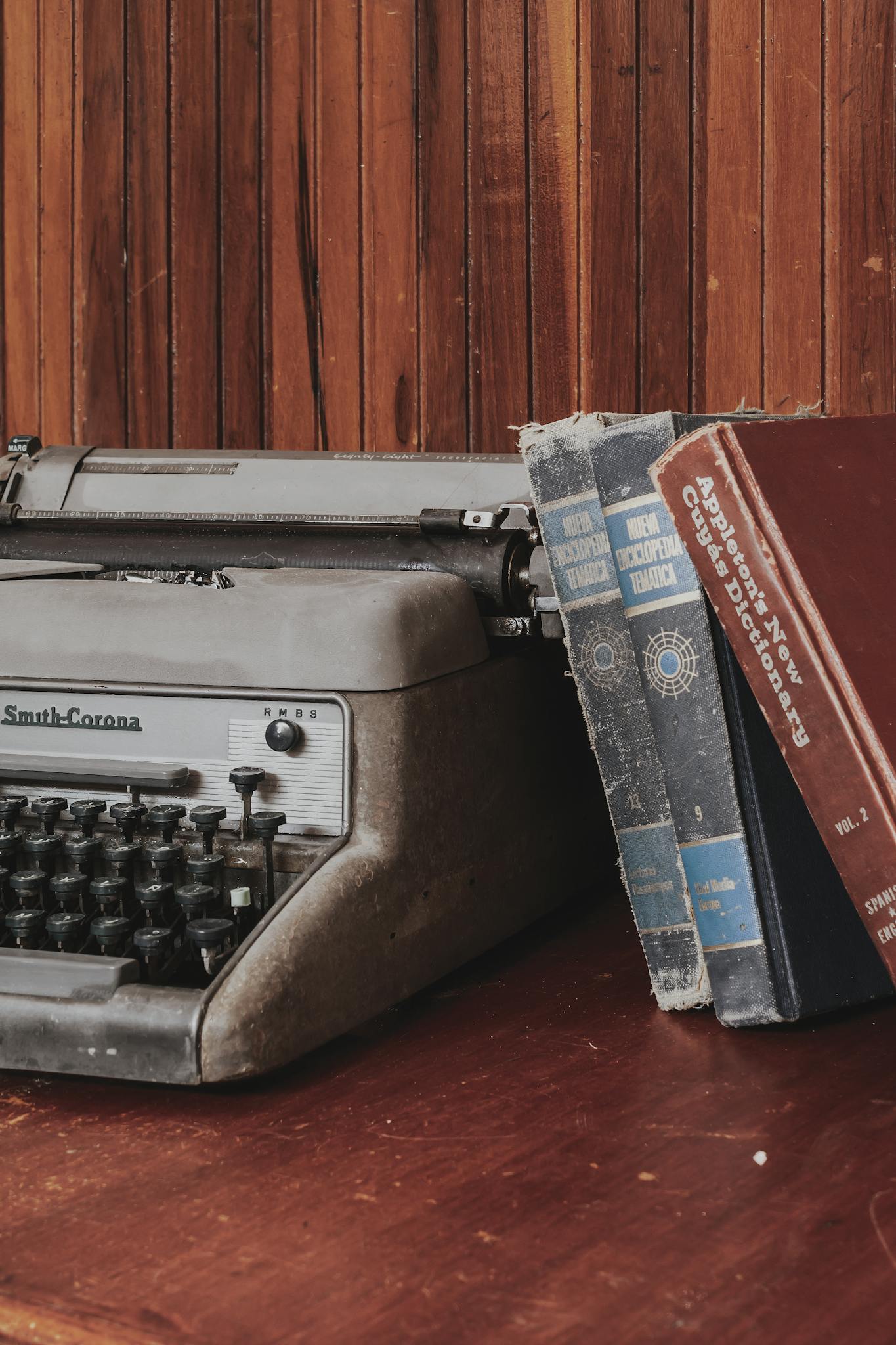 An antique typewriter next to aged books, evoking a nostalgic and literary ambiance.